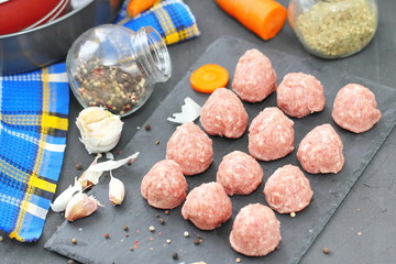 Raw meatballs on a chopping board with ingredients