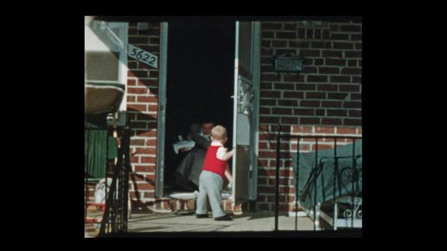 1953 LIttle boy holds open door for mom as they leave house