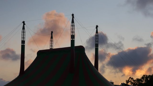 dark big top in the background with moving clouds at sunset