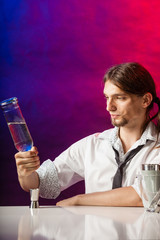 Barman fills shot glass.