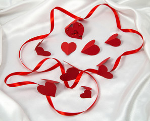 card, red satin ribbon in the texture with the cardboard red hearts on white fabric