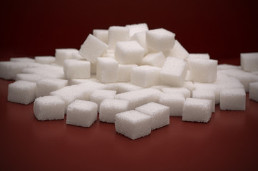 Pile of white sugar cobes on red background
