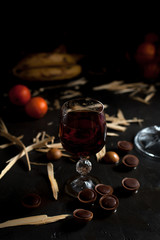 glasses with wine, chocolate and fruit on a dark background