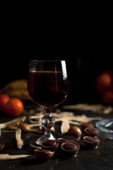 glasses with wine, chocolate and fruit on a dark background