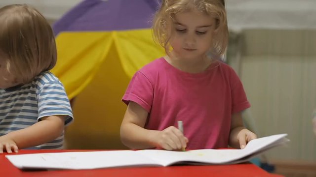 Two little children girl and boy sitting at table drawing. Brother and sister drawing with colorful crayons