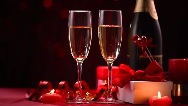 Valentine's Day romantic dinner. Date. Champagne, candles and gift box over holiday blinking background. 4K UHD video 3840x2160