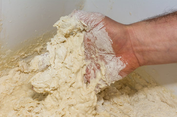 the chef's hands knead the dough to make pizza in the kitchen. Food, italian cuisine and cooking concept. Preparation of the Italian Pizza