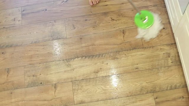 Woman mopping the kitchen floor with mop and bucket. Cleaning parquet floors in the living room