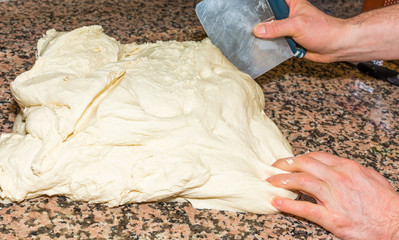 the chef's hands knead the dough to make pizza in the kitchen. Food, italian cuisine and cooking concept. Preparation of the Italian Pizza