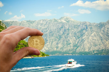 Hand holding golden bitcoin virtual money Shell with a golden bitcoin coin on the background of sea...