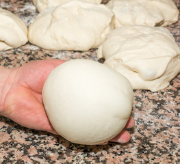 The chef prepares the balls of pizza dough on the floured table.Food, italian cuisine and cooking concept. Preparation of the Italian Pizza