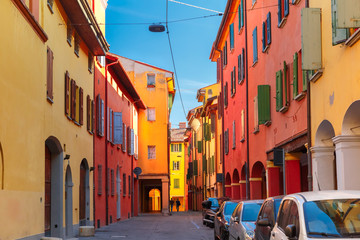 Medieval street portico with bright colored houses in the Old Town in the sunny day, Bologna, Emilia-Romagna, Italy