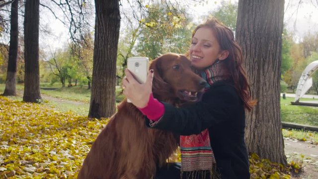 Girl makes selfie with dog setter in autumn park