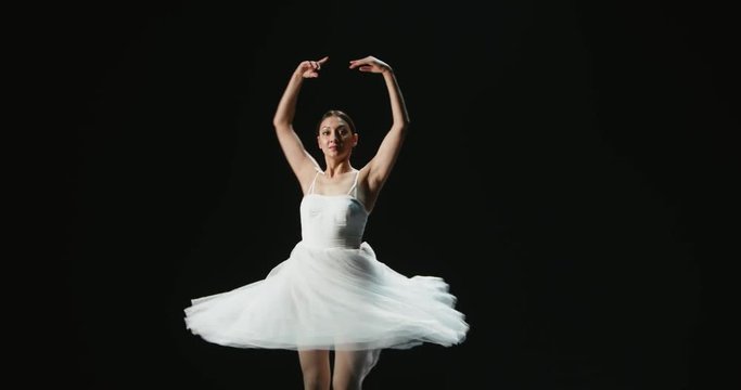 4K video footage beautiful pirouettes girl ballet dancer dancing on black background, slow motion