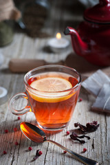 Glass with red tea on rustic wooden table.