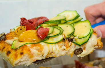 Closeup of a piece of pepperoni and zucchini pizza. Italian pizza.