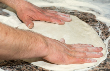 the chef's hands knead the dough to make pizza in the kitchen. Food, italian cuisine and cooking concept.Food, italian cuisine and cooking concept. Preparation of the Italian Pizza
