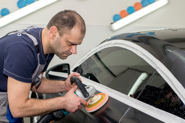 A man polishes a black car with a polisher
