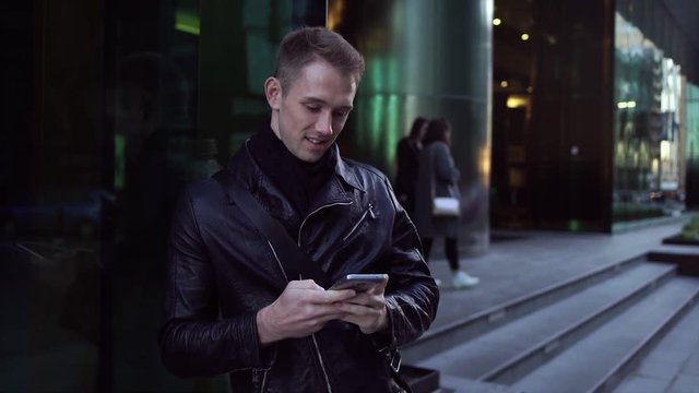 Young handsome man typing text message on smartphone smiling happy on street city 4K