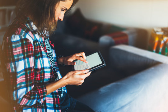 Hipster girl using tablet technology in home atmosphere, girl person holding computer with blank screen on background bokeh, female hands texting message on relax holiday
