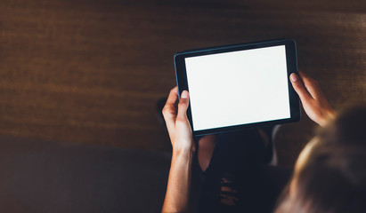 Hipster girl using tablet technology in home atmosphere, girl person holding computer with blank screen on background bokeh, female hands texting on relax holiday, mockup