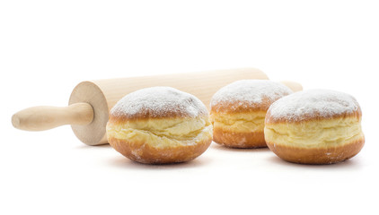 Sufganiyah three traditional doughnut with a rolling pin isolated on white background fresh baked with powered sugar and without hole.