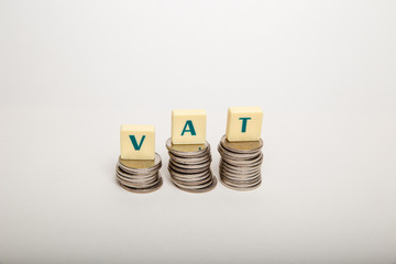 Stacks of coins with the letters VAT  (Value Added Tax) isolated on white background