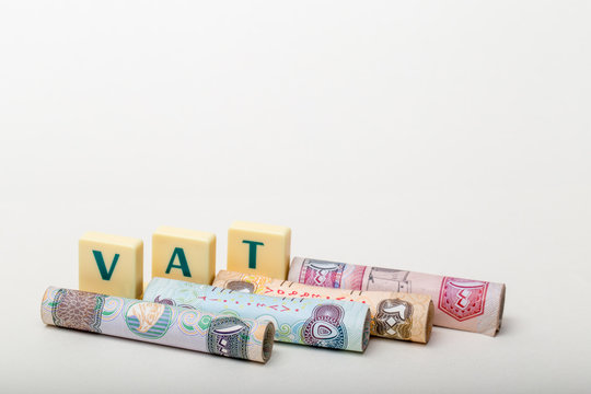 Stacks of  dirham banknotes with the letters VAT  (Value Added Tax) isolated on white background