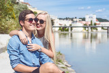 Junges Urlauberpaar sitzt am Innufer und hat Spaß