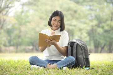 Asian Woman reading book with attractive smiling at garden. People lifestyle concept.