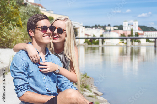 Junges Urlauberpaar sitzt am Innufer und hat Spaß