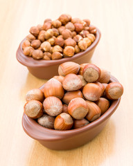 hazelnuts in clay bowl on wooden background