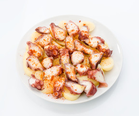 Marinated octopus sliced on potatoes isolated on white