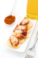 Marinated octopus sliced on potatoes isolated on white