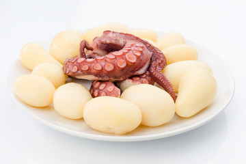 sliced octopus and raw potatoes in white crockery tray isolated on white