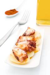 Marinated octopus sliced on potatoes isolated on white