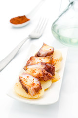 Marinated octopus sliced on potatoes isolated on white