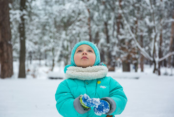 A child looks up at something interesting in the winter park