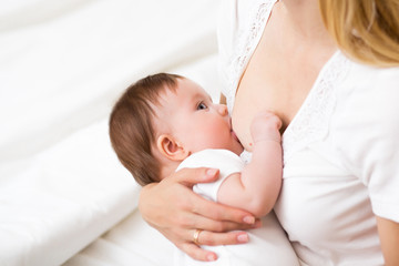 Obraz na płótnie Canvas Mother breast feeding and hugging her baby.Young mother feeding breast her babyboy at home in white room. Mom breastfeeding her child whith breast milk