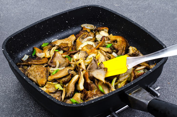 Oyster mushrooms fried with onions in frying pan