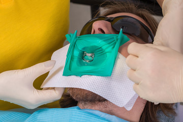 Patient getting dental treatment at dentist office with dental rubber dam protection and smart...