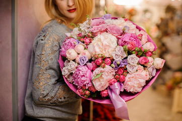 elegant girl smiles holds a huge bouquet of different pink and purple flowers