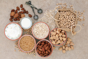 Obraz na płótnie Canvas Vegan health food with nuts, seeds, soy beans, oats, soya milk, chunks and yoghurt. Foods high in fibre, antioxidants, anthocyanins, vitamins and minerals. Top view on natural hemp paper background.