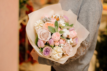woman holds a big bouquet with roses, pion-shaped roses and eucalyptus