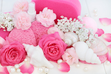 Beauty treatment cleansing and spa products with pink roses and carnation flowers, seashell soaps, bath bomb, body lotion, seashell soaps, sponges and decorative pearls. 