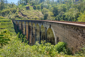 Fototapeta na wymiar The famous Nine Arches Bridge in the Uva province, located between Demodara and Ella in the highlands of Sri Lanka. The bridge was build in 1921, only from bricks, rocks and cement