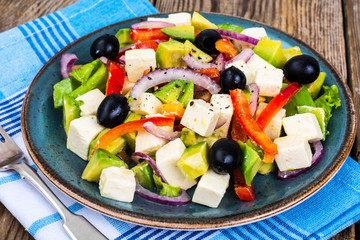 Vegetable salad with feta on wooden background