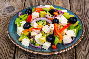 Vegetable salad with feta on wooden background