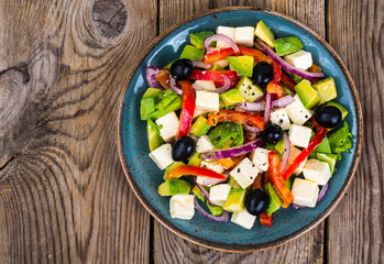 Vegetable salad with feta on wooden background