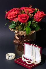 Vertical photo of the flowers bouquet near box with pearls on dark